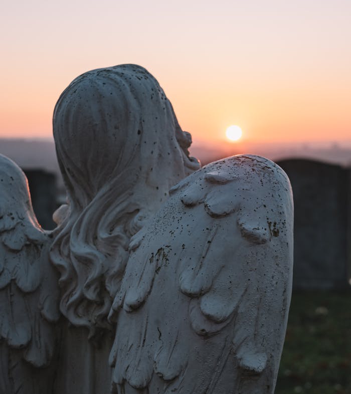 The Art of Drawing Readers In: Your attractive post title goes here A contemplative angel statue in a cemetery, facing a serene sunset sky.
