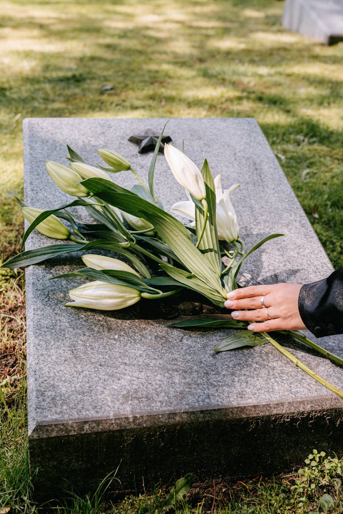 Mastering the First Impression: Your intriguing post title goes here White lilies on a gravestone symbolize remembrance in an outdoor cemetery setting.